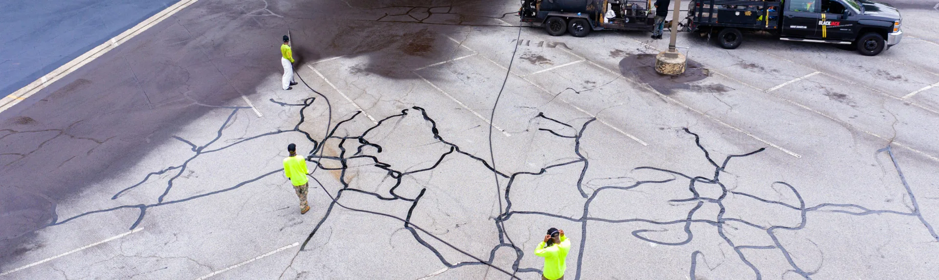 pave america employees completing crack filling services in a parking lot