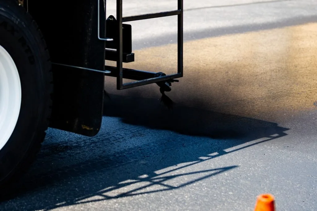 sealcoating truck spraying pavement