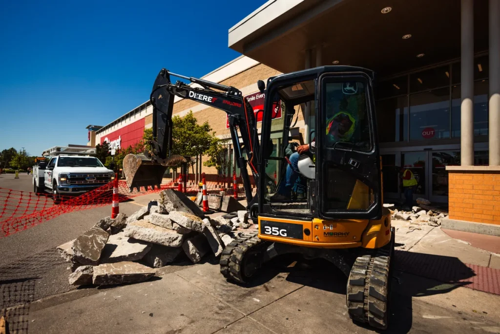 pave america employee in an excavator in front of a parking lot