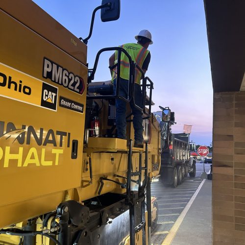 Cincinnati Asphalt employee on branded CAT machine performing services.