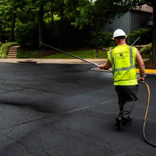 Dominion Paving employee performing sealcoating on site.