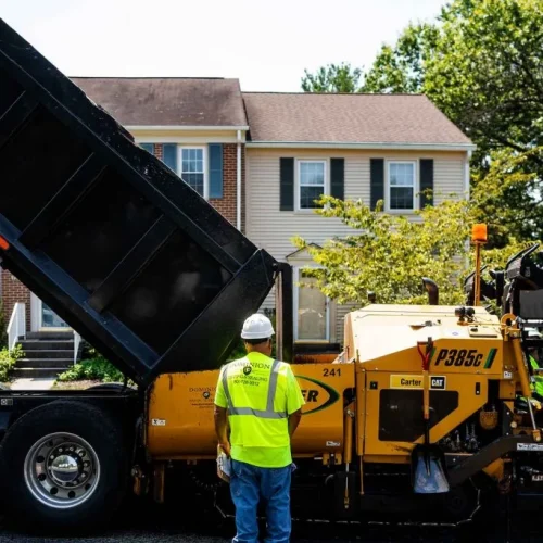 Dominion Paving employee in front of machine on site.