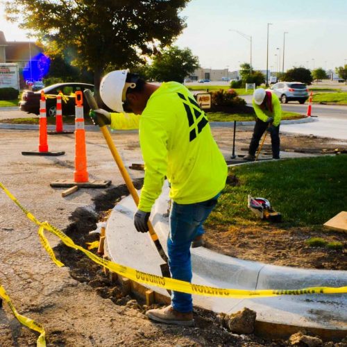 Kansas Asphalt employee on jobsite wearing yellow safety shirt with logo.