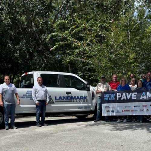 Landmark Paving employees standing with Pave America sign in front of Landmark truck.
