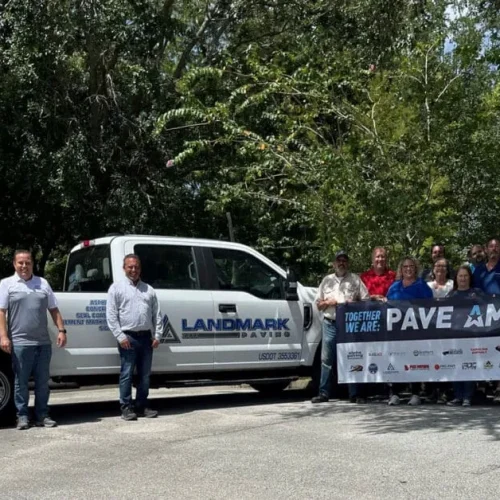 Landmark Paving employees standing with Pave America sign in front of Landmark truck.