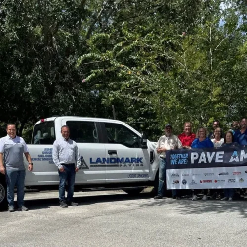 Landmark Paving employees standing with Pave America sign in front of Landmark truck.