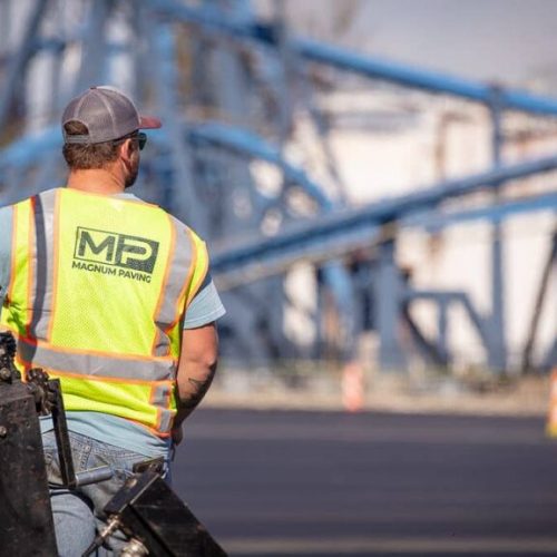 Magnum Paving employee from behind riding company truck on paving project job site.